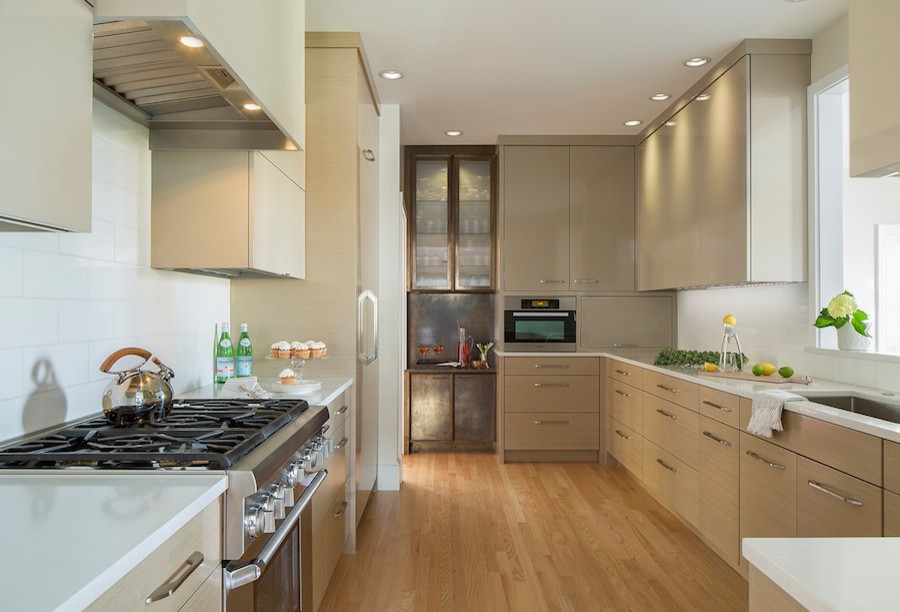 This is an example of a contemporary galley separate kitchen in Boston with an undermount sink, flat-panel cabinets, light wood cabinets, quartz benchtops, white splashback, glass tile splashback, panelled appliances, light hardwood floors and no island.