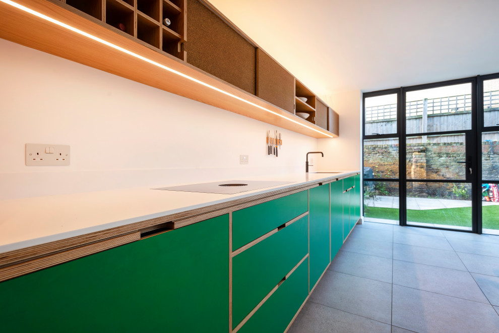 Photo of a mid-sized scandinavian single-wall eat-in kitchen in London with an integrated sink, recessed-panel cabinets, green cabinets, panelled appliances, porcelain floors, no island, grey floor and white benchtop.