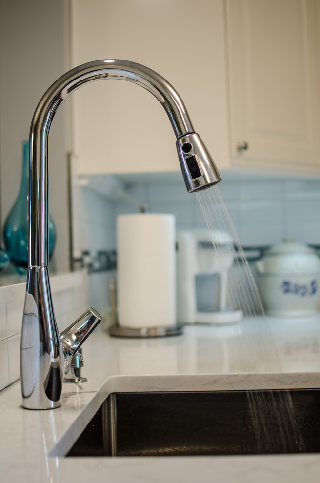Enclosed kitchen - mid-sized transitional l-shaped vinyl floor enclosed kitchen idea in DC Metro with an undermount sink, shaker cabinets, quartz countertops, white backsplash, ceramic backsplash, black appliances and no island