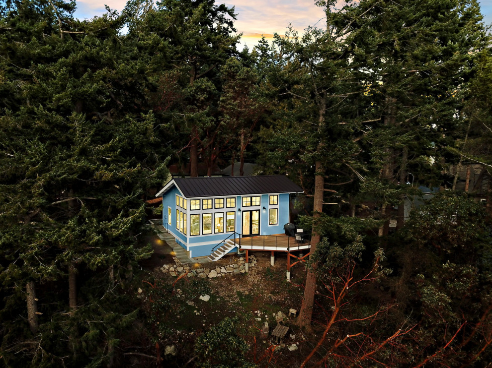На фото: маленький, одноэтажный, деревянный, синий мини дом в морском стиле с полувальмовой крышей, металлической крышей и коричневой крышей для на участке и в саду