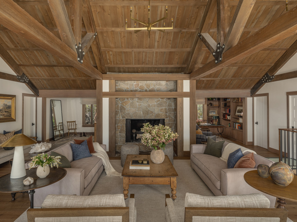 Living room - large rustic open concept medium tone wood floor, brown floor and exposed beam living room idea with white walls, a standard fireplace and a stone fireplace