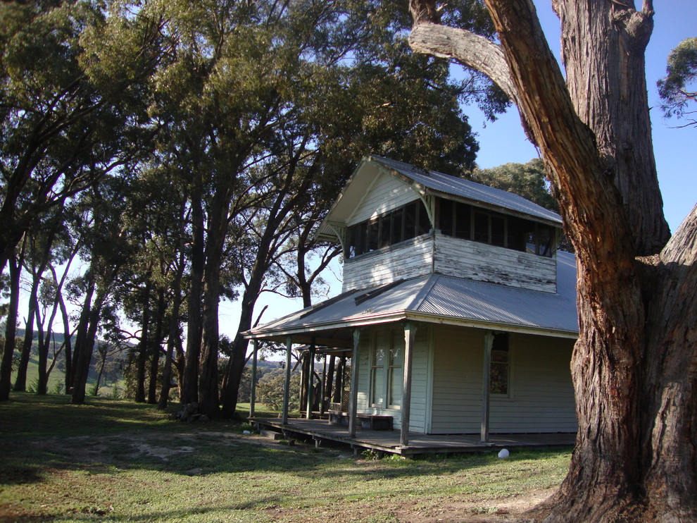 Photo of a mid-sized country two-storey white exterior in Melbourne with wood siding and a hip roof.