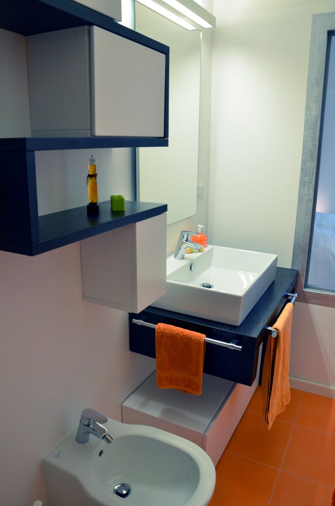 Photo of a small modern 3/4 bathroom in Milan with flat-panel cabinets, medium wood cabinets, a double shower, a two-piece toilet, orange tile, porcelain tile, orange walls, porcelain floors, a vessel sink and wood benchtops.