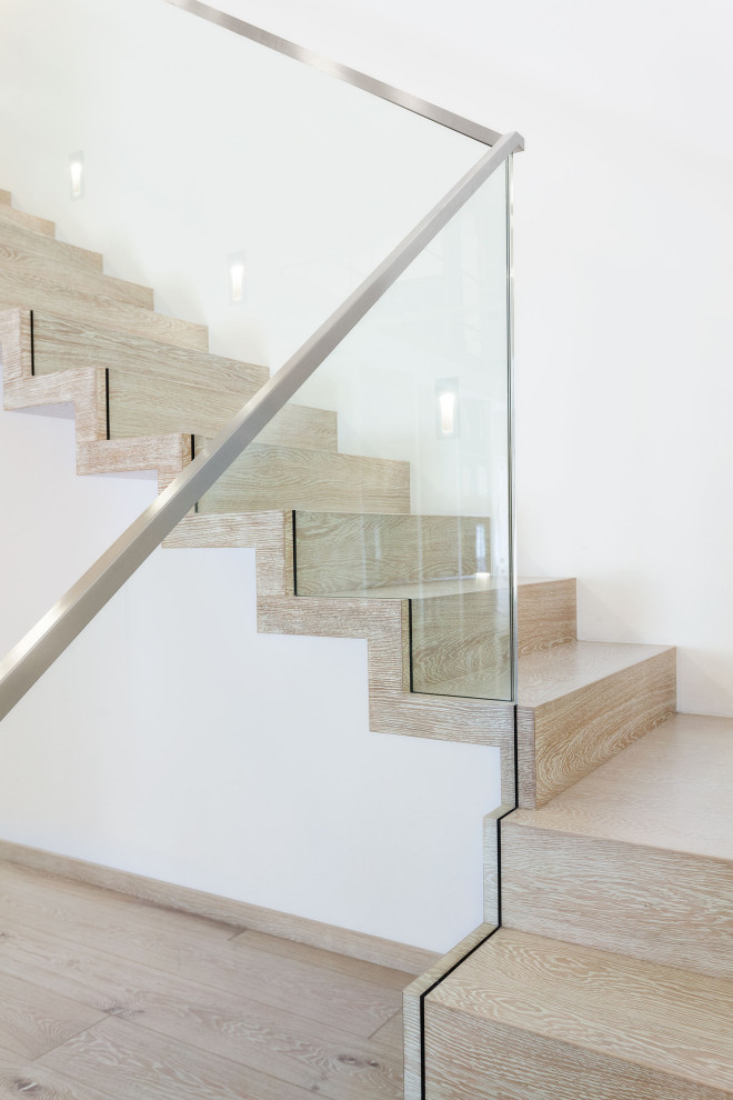На фото: лестница на больцах, среднего размера в современном стиле с крашенными деревянными ступенями, крашенными деревянными подступенками и стеклянными перилами
