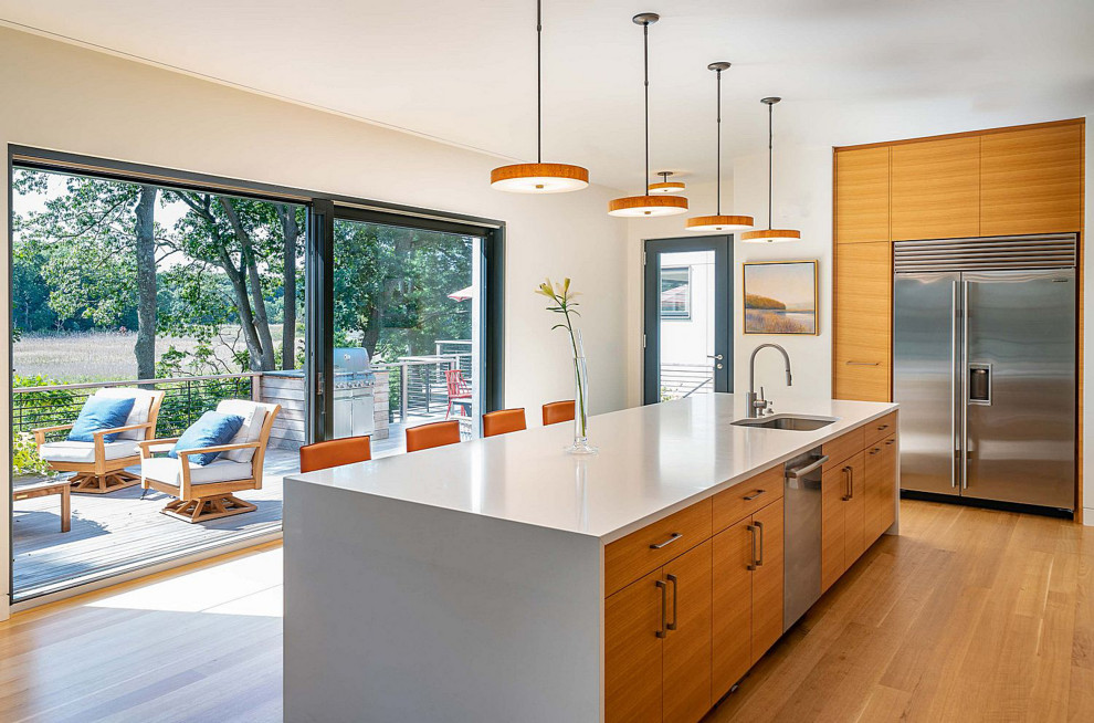Design ideas for a mid-sized contemporary kitchen in Boston with a single-bowl sink, flat-panel cabinets, light wood cabinets, stainless steel appliances, light hardwood floors, with island and white benchtop.