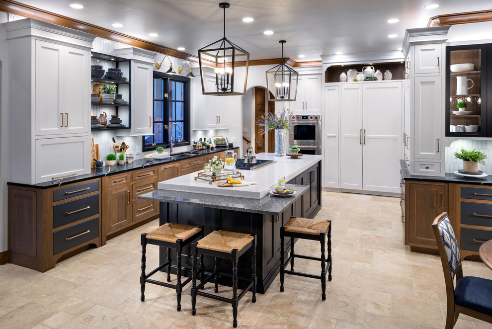 Photo of a large country l-shaped separate kitchen in Oklahoma City with an undermount sink, white cabinets, quartz benchtops, white splashback, porcelain splashback, panelled appliances, marble floors, with island and black benchtop.