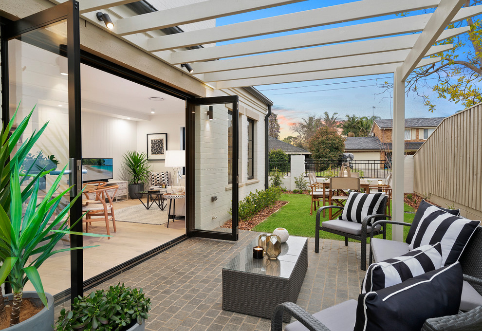 Inspiration for a small transitional backyard patio in Sydney with natural stone pavers and a pergola.