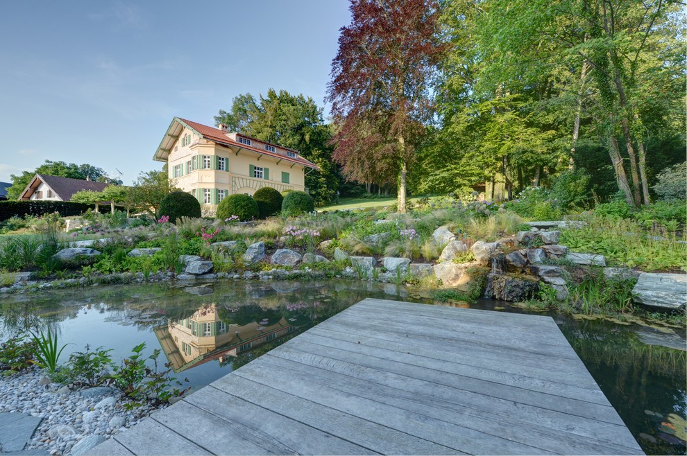 Mittelgroßer Uriger Schwimmteich hinter dem Haus in individueller Form mit Natursteinplatten in München