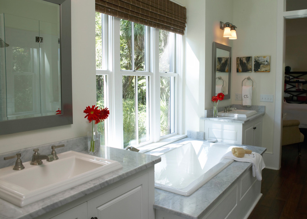 This is an example of a large traditional master bathroom in Milwaukee with a drop-in sink, flat-panel cabinets, white cabinets, marble benchtops, a drop-in tub, an alcove shower, beige walls and dark hardwood floors.