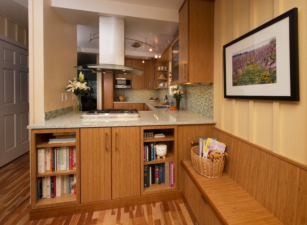 This is an example of a small contemporary u-shaped eat-in kitchen in San Francisco with an undermount sink, flat-panel cabinets, medium wood cabinets, recycled glass benchtops, green splashback, glass tile splashback, stainless steel appliances, medium hardwood floors and a peninsula.