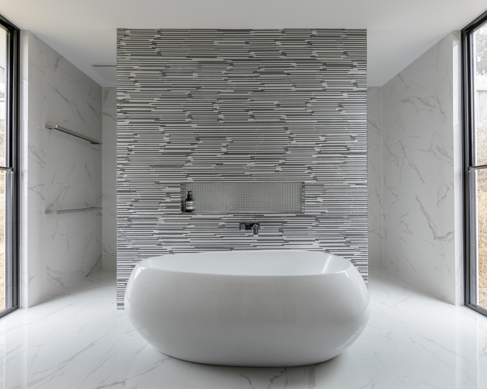 Inspiration for an expansive contemporary master wet room bathroom in Melbourne with a freestanding tub, gray tile, glass tile and marble floors.