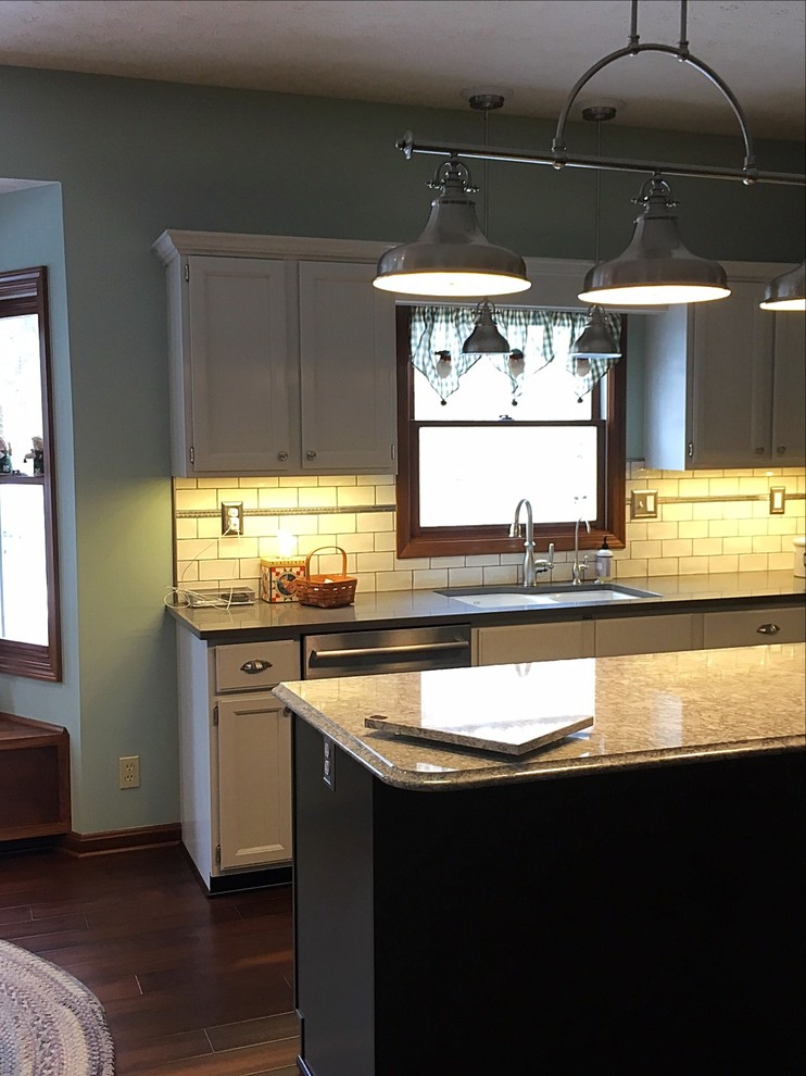 Enclosed kitchen - mid-sized transitional u-shaped medium tone wood floor enclosed kitchen idea with an undermount sink, white cabinets, quartz countertops, white backsplash, subway tile backsplash, stainless steel appliances and an island