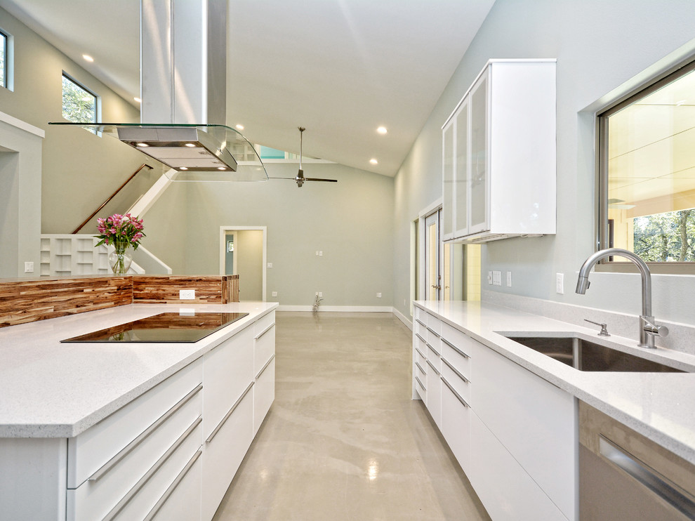 Inspiration for a mid-sized eclectic l-shaped open plan kitchen in Austin with flat-panel cabinets, white cabinets, quartz benchtops, with island, an undermount sink, white splashback, stone slab splashback, stainless steel appliances and concrete floors.