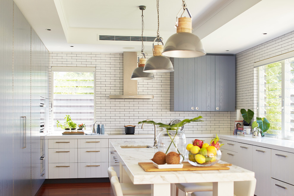 Inspiration for a large beach style u-shaped eat-in kitchen in Perth with an undermount sink, flat-panel cabinets, marble benchtops, white splashback, subway tile splashback, medium hardwood floors and with island.
