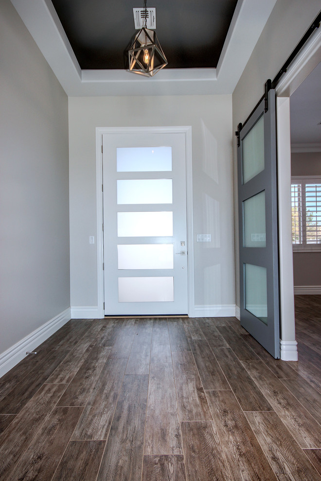 This is an example of a mid-sized transitional front door in Phoenix with grey walls, ceramic floors, a single front door, a white front door and brown floor.