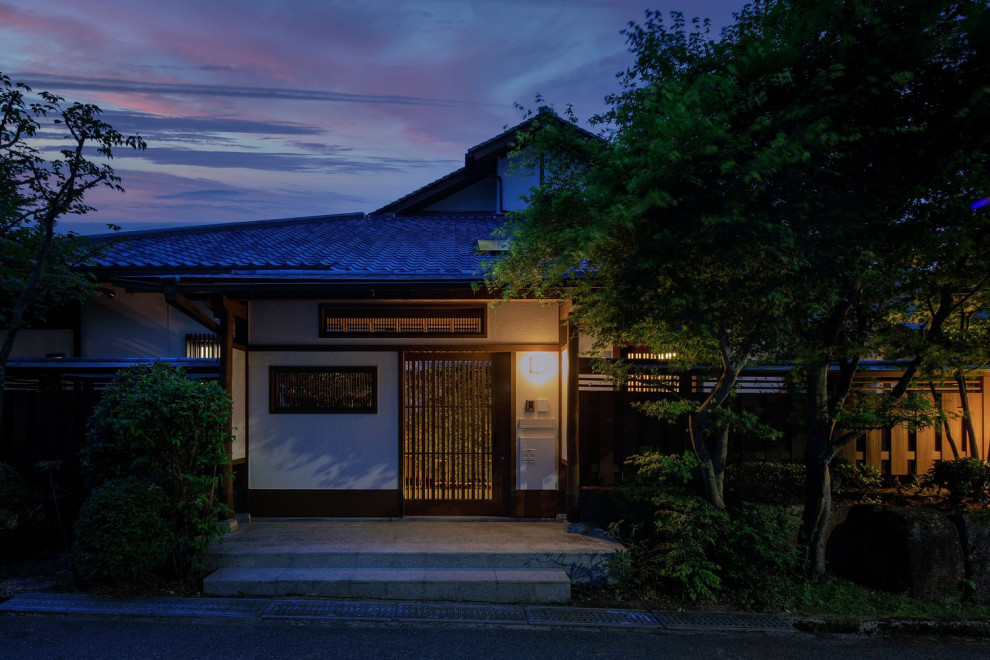 This is an example of a large traditional entrance in Osaka with white walls, granite flooring, a brown front door, grey floors and a wood ceiling.