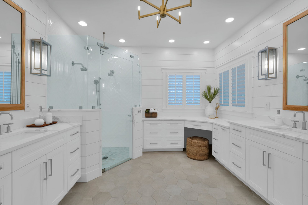 This is an example of a large beach style ensuite bathroom in Jacksonville with recessed-panel cabinets, white cabinets, a corner shower, white tiles, ceramic tiles, engineered stone worktops, a hinged door, white worktops, a wall niche, double sinks and a built in vanity unit.