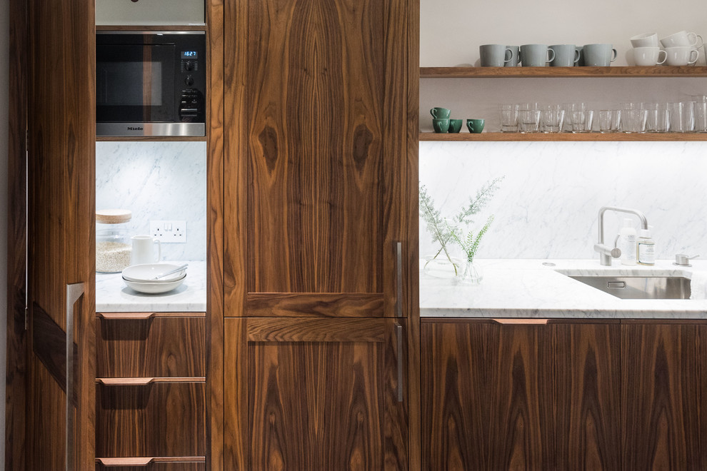 This is an example of a mid-sized midcentury kitchen in London with dark wood cabinets, marble benchtops and with island.