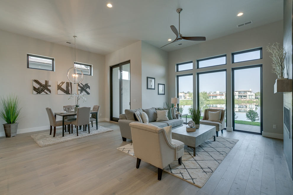 Photo of a large modern open concept living room in Boise with grey walls, light hardwood floors, a ribbon fireplace, a tile fireplace surround, no tv and beige floor.