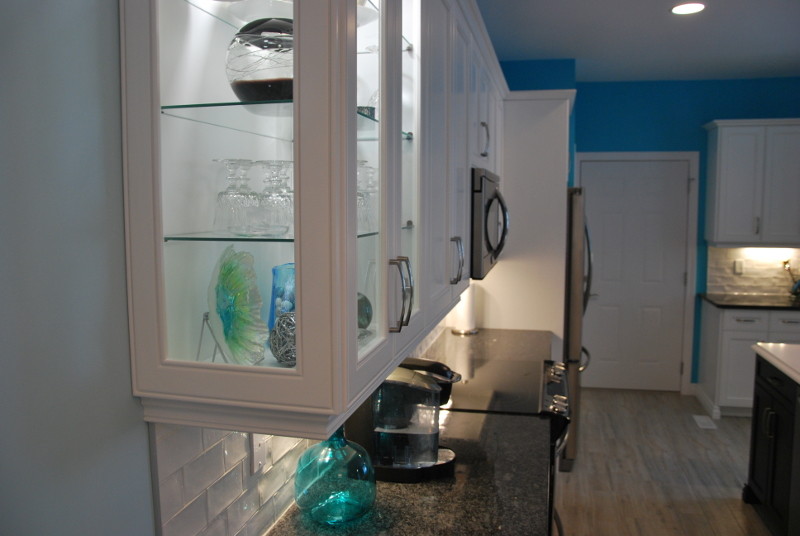 Kitchen - mid-sized transitional l-shaped porcelain tile and beige floor kitchen idea in Toronto with an undermount sink, recessed-panel cabinets, white cabinets, granite countertops, white backsplash, subway tile backsplash, stainless steel appliances, an island and black countertops