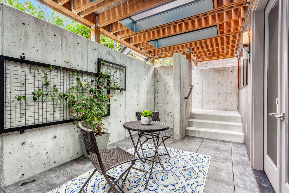 This is an example of a mid-sized industrial backyard patio in Seattle with a vertical garden, concrete slab and a roof extension.