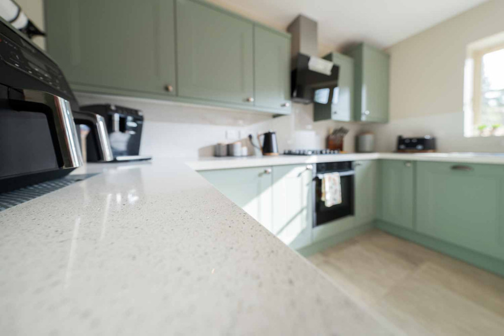 Large u-shaped ceramic tile and beige floor eat-in kitchen photo with shaker cabinets, green cabinets, quartz countertops, white backsplash, stainless steel appliances, no island and white countertops