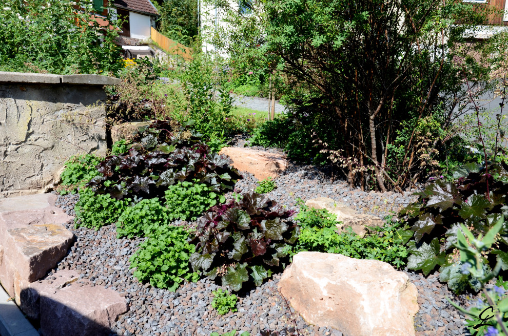 Diseño de jardín de estilo de casa de campo de tamaño medio en verano en patio delantero con parterre de flores, exposición total al sol y adoquines de piedra natural