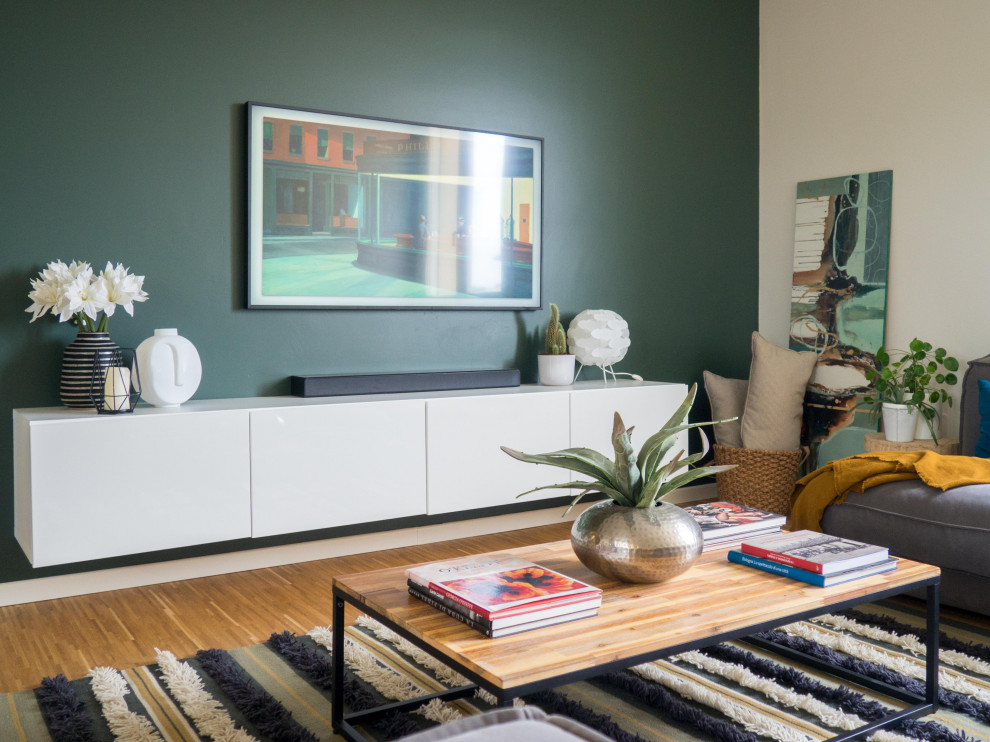 Immagine di un soggiorno contemporaneo aperto e di medie dimensioni con parquet chiaro, pareti verdi e TV a parete