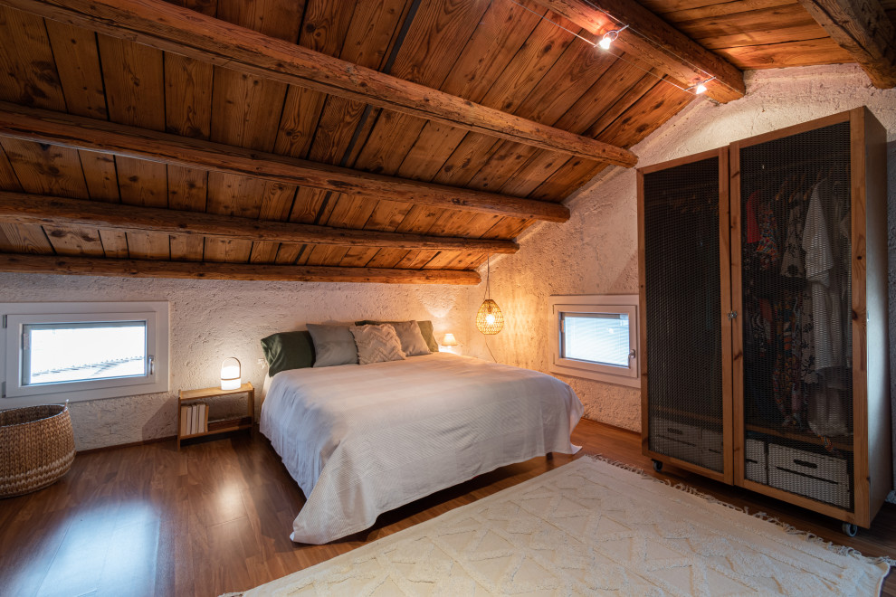 Modelo de dormitorio principal rural de tamaño medio con paredes blancas, suelo de linóleo, suelo naranja y vigas vistas