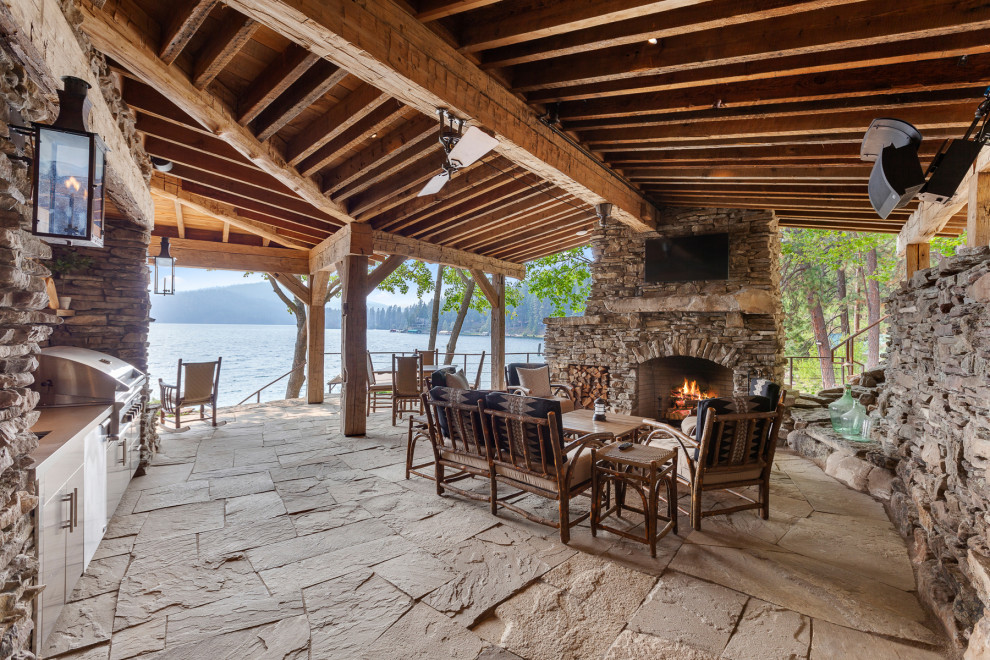 Cette image montre une terrasse chalet avec une cuisine d'été, des pavés en pierre naturelle et une extension de toiture.