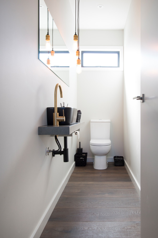Design ideas for a contemporary powder room in Other with a one-piece toilet, white walls, medium hardwood floors, engineered quartz benchtops, brown floor, grey benchtops and a wall-mount sink.
