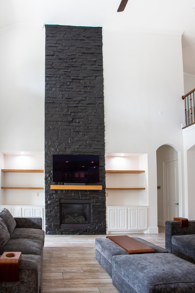 На фото: большая открытая гостиная комната в стиле модернизм с черными стенами, стандартным камином, фасадом камина из кирпича и отдельно стоящим телевизором с