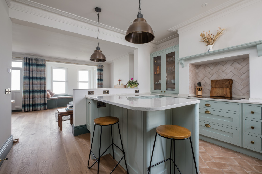 This is an example of a nautical kitchen in Sussex with a submerged sink, shaker cabinets, black appliances, a breakfast bar, brown floors, white worktops and a chimney breast.
