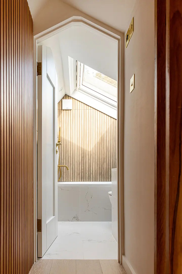 The bathroom at House CN by SASI Studio is designed as a calm, light-filled retreat within this East London terraced house renovation. A rooflight brings natural light into the compact space, highligh