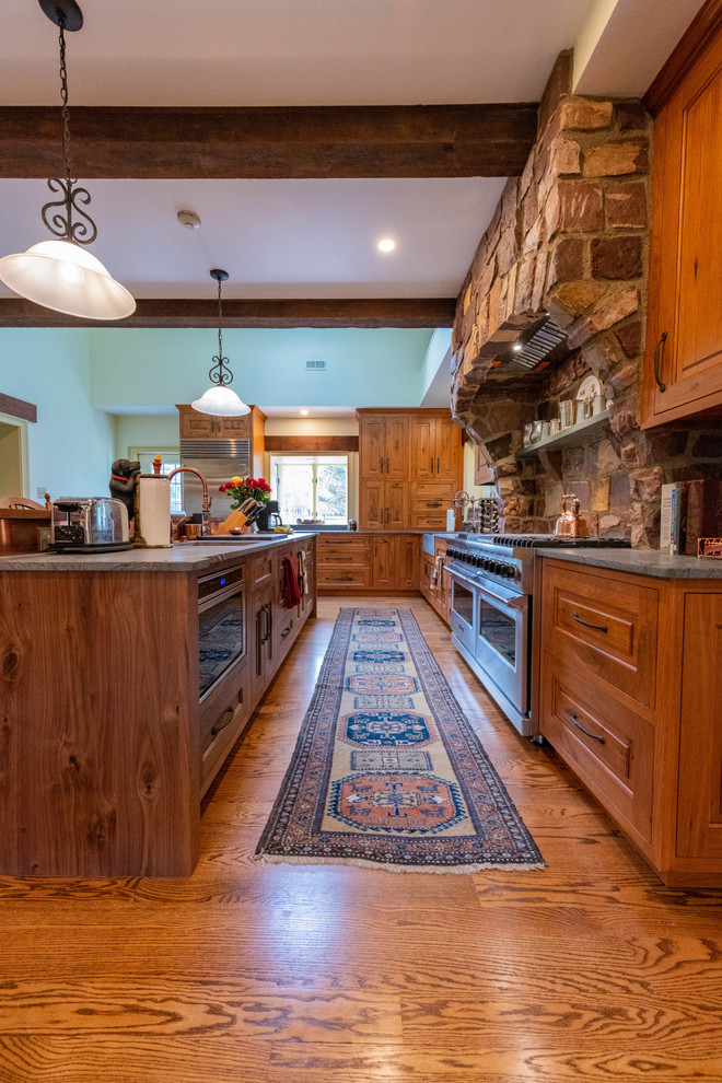 Eat-in kitchen - large rustic l-shaped medium tone wood floor and brown floor eat-in kitchen idea in Philadelphia with a farmhouse sink, raised-panel cabinets, distressed cabinets, soapstone countertops, multicolored backsplash, stone tile backsplash, stainless steel appliances, an island and blue countertops