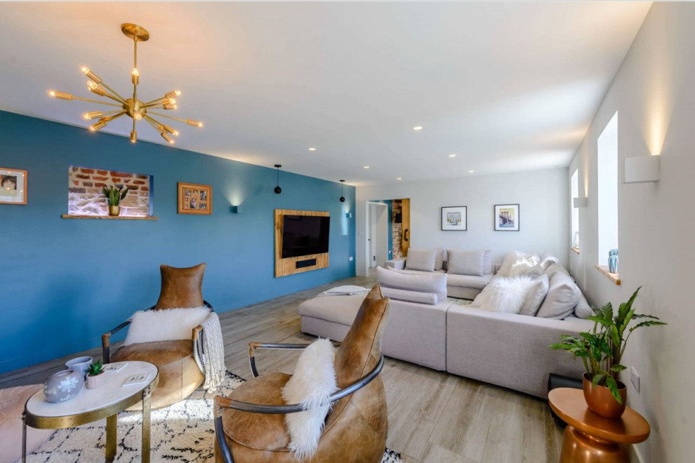 This is an example of a large industrial grey and teal enclosed living room in Kent with blue walls, porcelain flooring, a wall mounted tv, grey floors, brick walls and feature lighting.