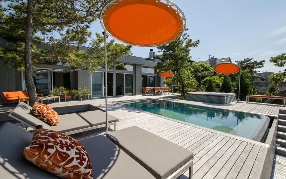 Mid-sized midcentury backyard rectangular infinity pool in New York with a hot tub and decking.