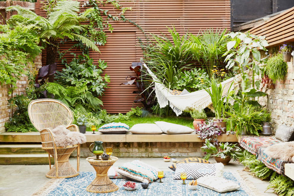This is an example of a tropical backyard garden in London with concrete pavers.