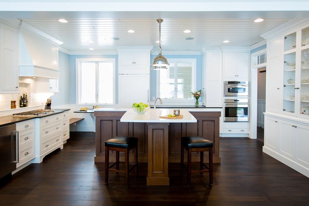 Design ideas for a mid-sized beach style u-shaped eat-in kitchen in Other with an undermount sink, recessed-panel cabinets, white cabinets, granite benchtops, white splashback, subway tile splashback, stainless steel appliances, dark hardwood floors and with island.