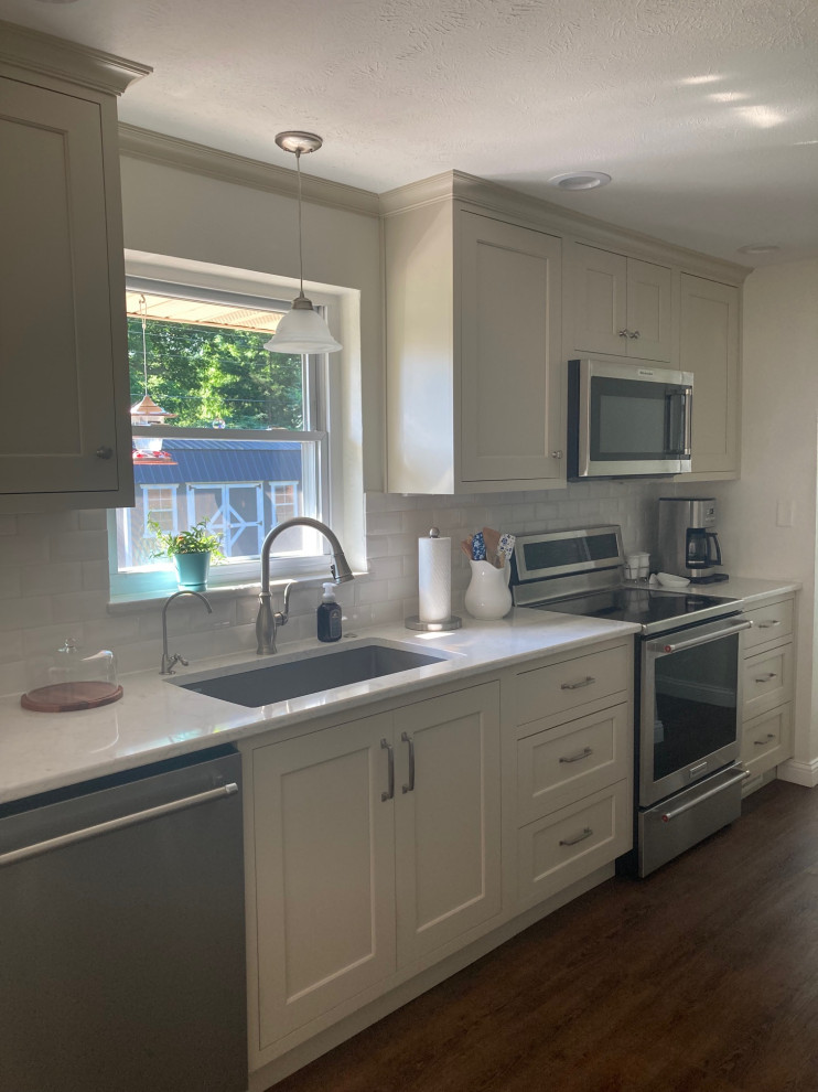 This is an example of a small traditional galley eat-in kitchen in Other with an undermount sink, beige cabinets, quartz benchtops, white splashback, ceramic splashback, stainless steel appliances, medium hardwood floors, no island and white benchtop.