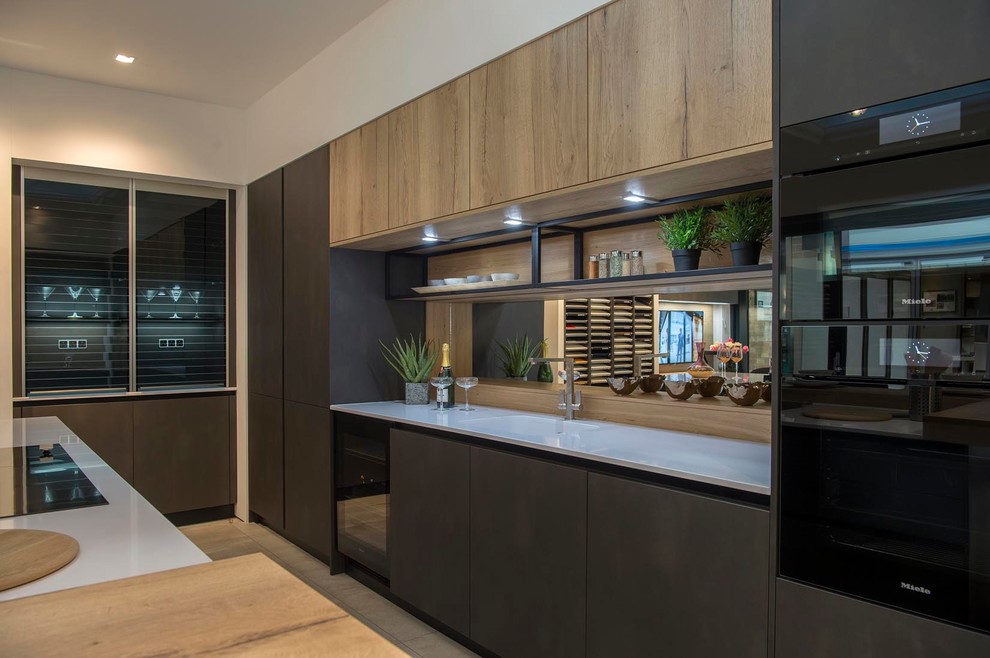 Design ideas for a large contemporary galley eat-in kitchen in Other with an integrated sink, flat-panel cabinets, grey cabinets, quartzite benchtops, metallic splashback, mirror splashback, black appliances, ceramic floors, with island, beige floor and white benchtop.