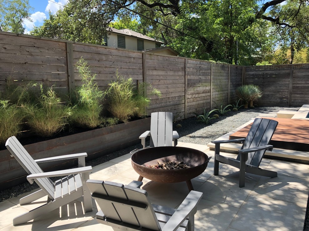 Midcentury backyard patio in Austin with a fire feature, concrete slab and no cover.