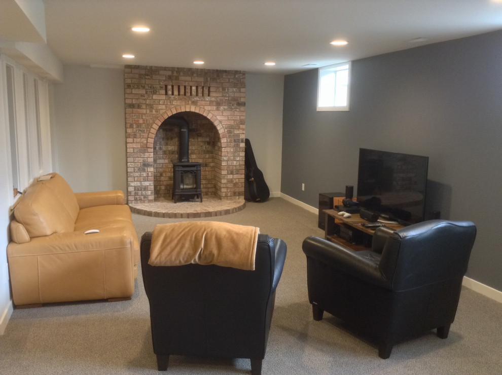 Large trendy look-out carpeted basement photo in Vancouver with gray walls, a wood stove and a brick fireplace