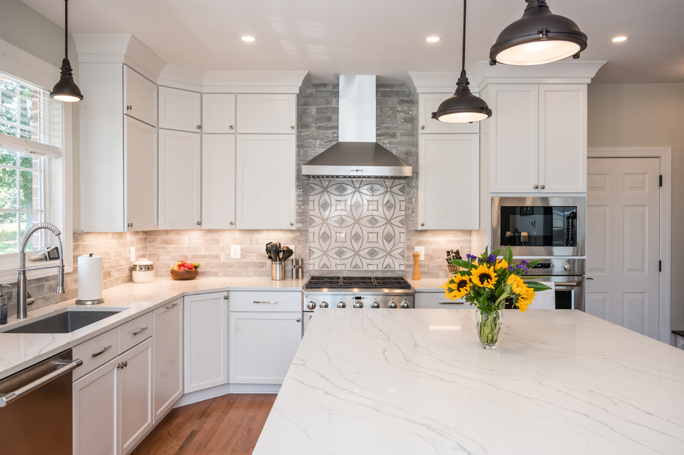 Inspiration for a large transitional u-shaped light wood floor open concept kitchen remodel in Baltimore with an undermount sink, shaker cabinets, white cabinets, quartz countertops, gray backsplash, ceramic backsplash, stainless steel appliances, an island and white countertops