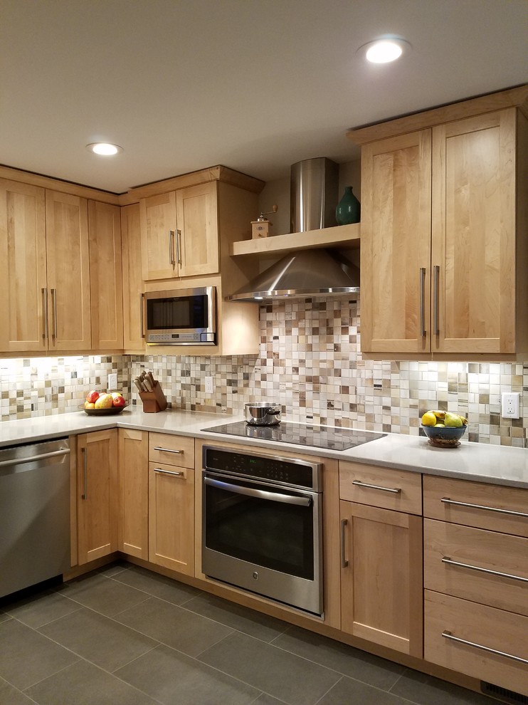 Example of a mid-sized transitional u-shaped ceramic tile open concept kitchen design with an undermount sink, shaker cabinets, light wood cabinets, quartz countertops, beige backsplash, porcelain backsplash, stainless steel appliances and a peninsula