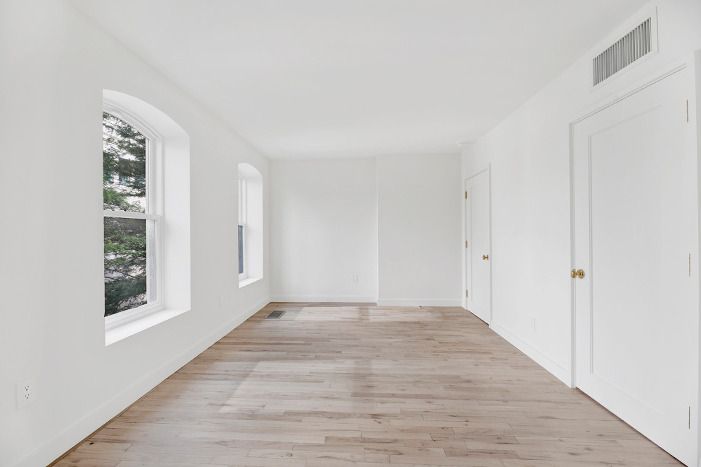 Großes Klassisches Schlafzimmer mit weißer Wandfarbe, hellem Holzboden und beigem Boden in New York