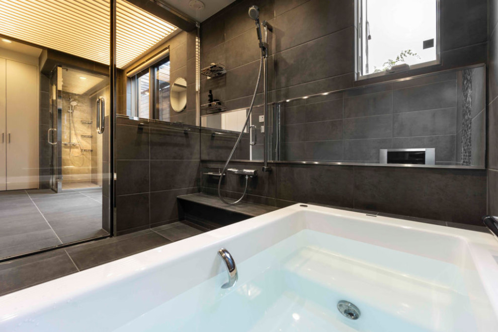 Inspiration for a modern bathroom with a built-in bath, black tiles, black walls, black floors and a drop ceiling.