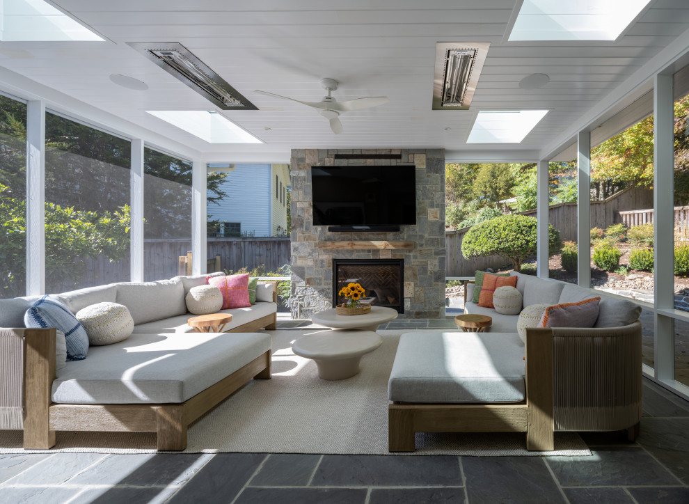 This is an example of a contemporary screened-in porch design in DC Metro with a fireplace and a roof extension.
