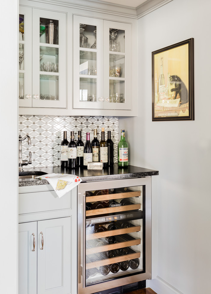 Design ideas for a traditional galley home bar in Boston with an undermount sink, beaded inset cabinets, grey cabinets, granite benchtops, grey splashback, mosaic tile splashback and medium hardwood floors.