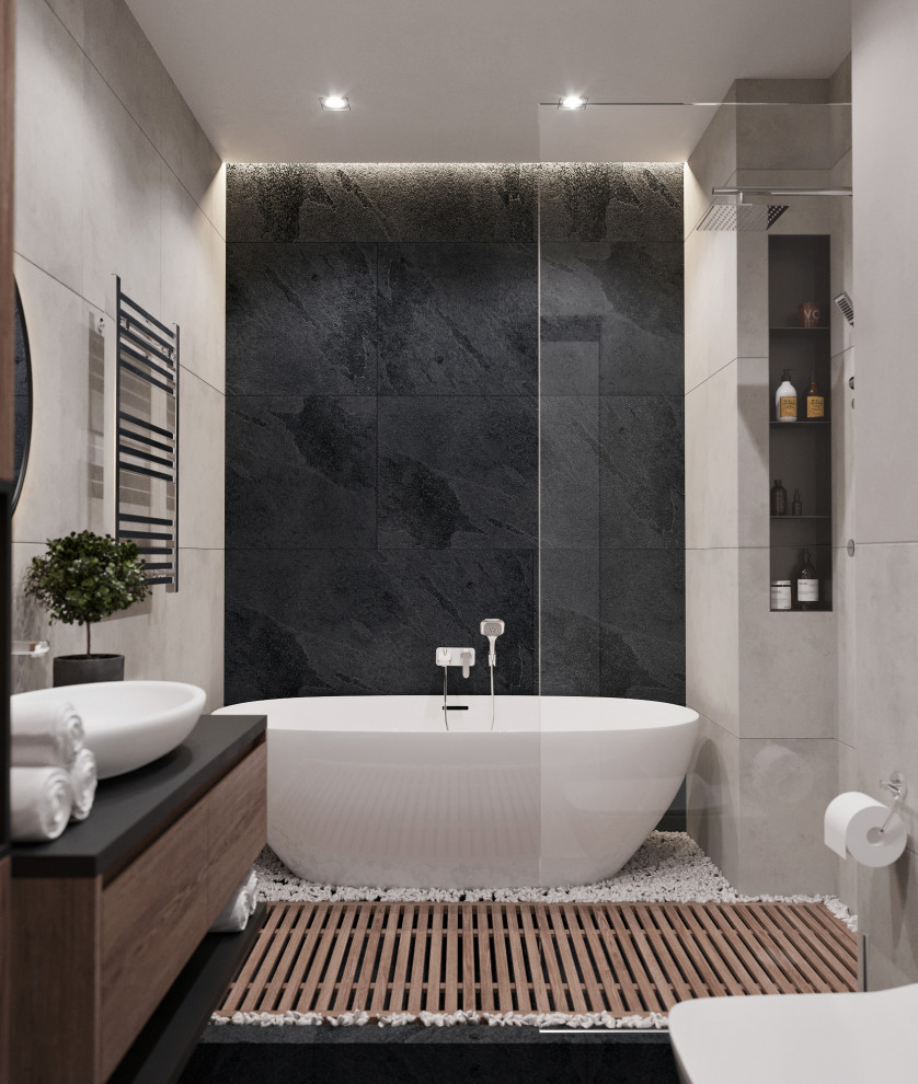 This is an example of a mid-sized contemporary master bathroom in Other with flat-panel cabinets, a freestanding tub, a shower/bathtub combo, a wall-mount toilet, gray tile, porcelain tile, grey walls, a vessel sink, black floor, a shower curtain, black benchtops, medium wood cabinets, porcelain floors and solid surface benchtops.